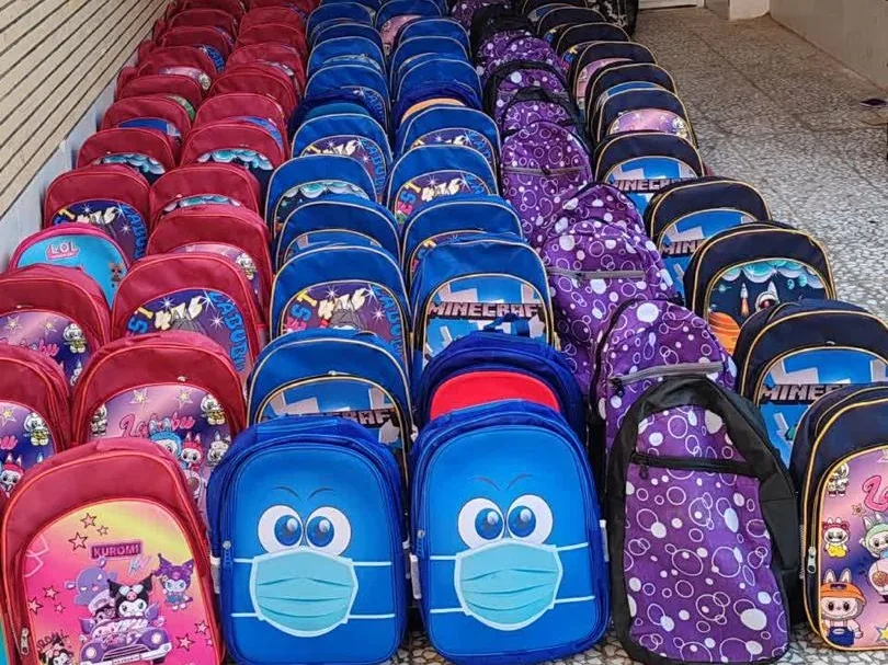 Rows of new children's backpacks lined up on the floor