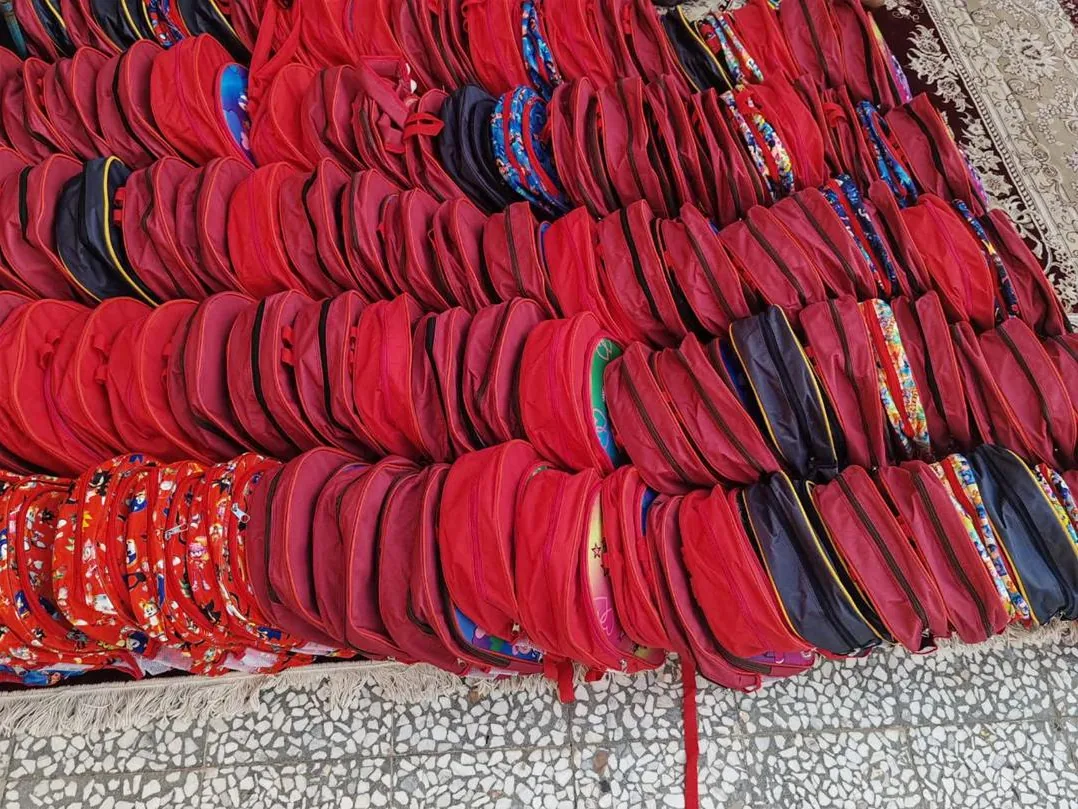 Dozens of red and navy backpacks laid out in rows